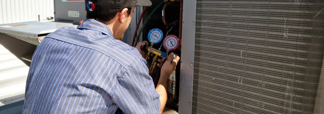 HVAC technician servicing a condenser unit in Dalton